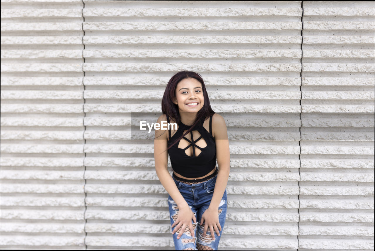 Portrait of smiling girl posing with casual clothes on a wall