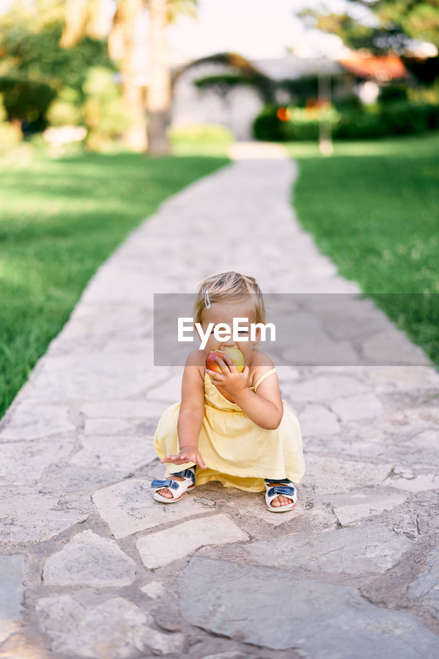 PORTRAIT OF A BOY SITTING ON FOOTPATH