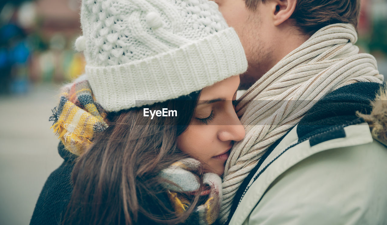 Close-up of couple embracing while wearing warm clothing in city
