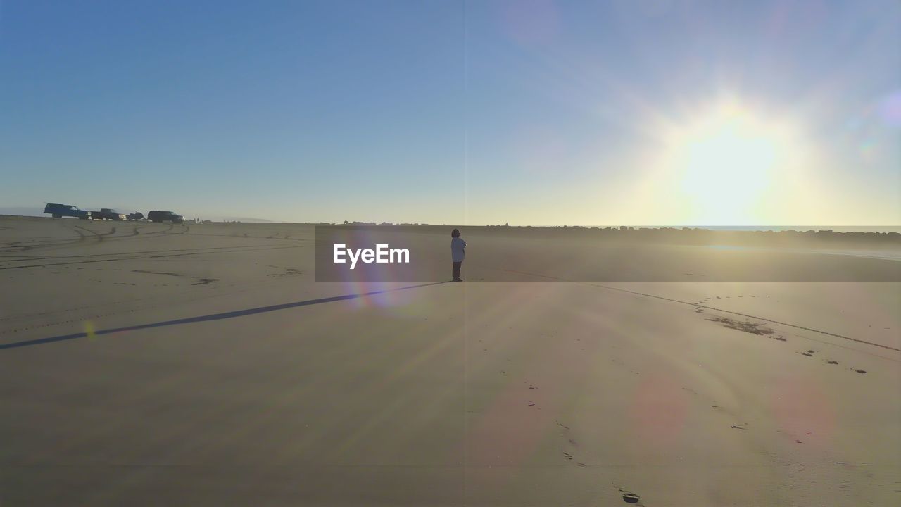 Person standing at sandy beach against sky