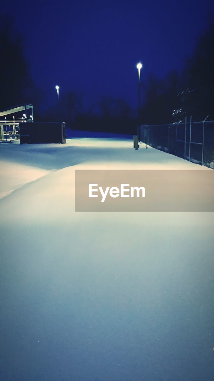 Snowcapped illuminated street at night during winter