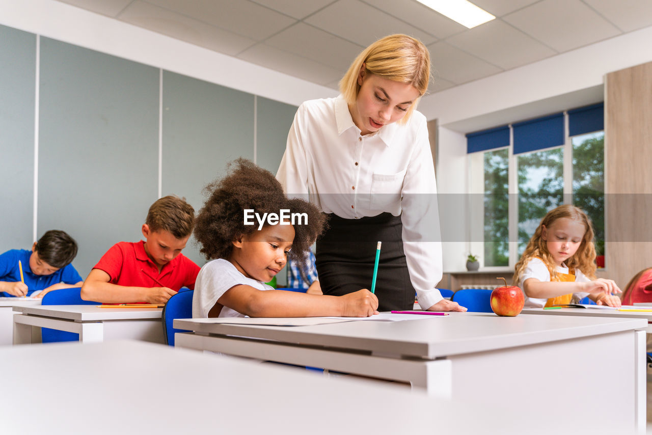 Teacher teaching student at classroom