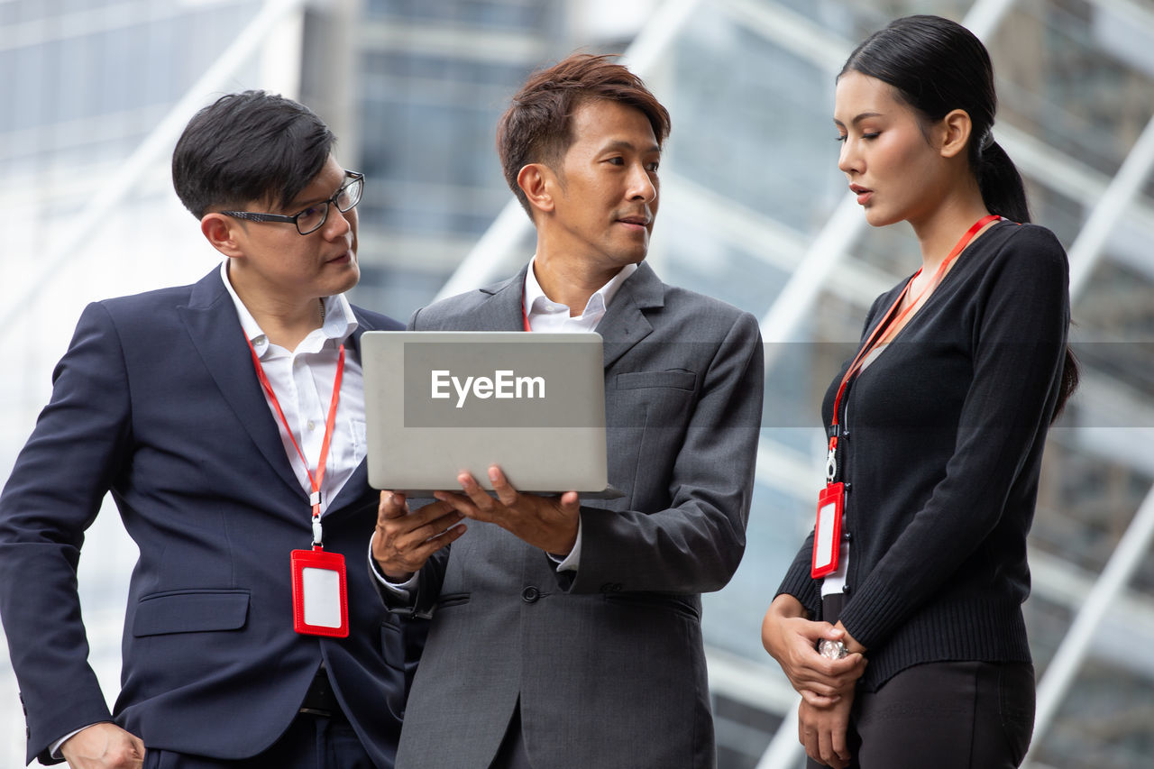 Business people using laptop while standing outdoors