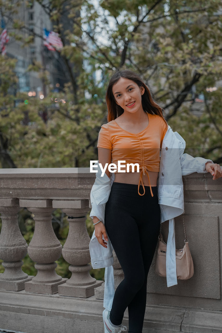 portrait of young woman standing against building