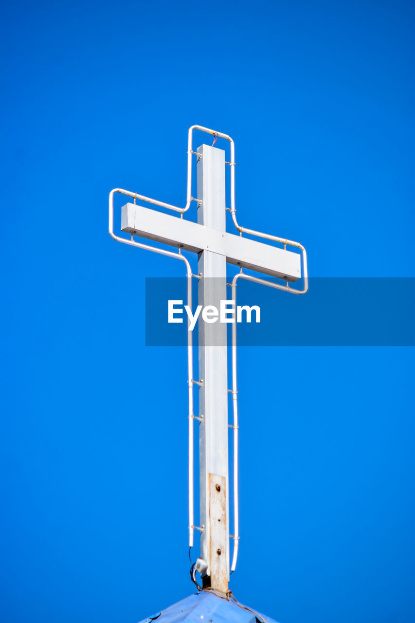 LOW ANGLE VIEW OF CROSS SIGN AGAINST BLUE SKY