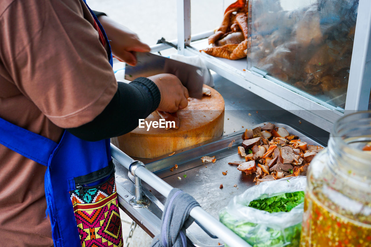 Delicious stewed ear pork at the street food. motion blurred hand of seller chops the pork on board.