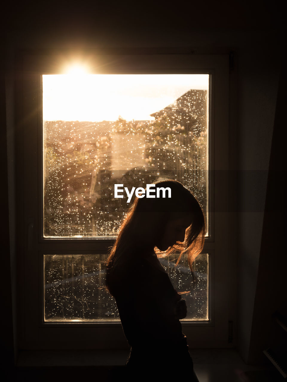 Side view of silhouette woman standing against window