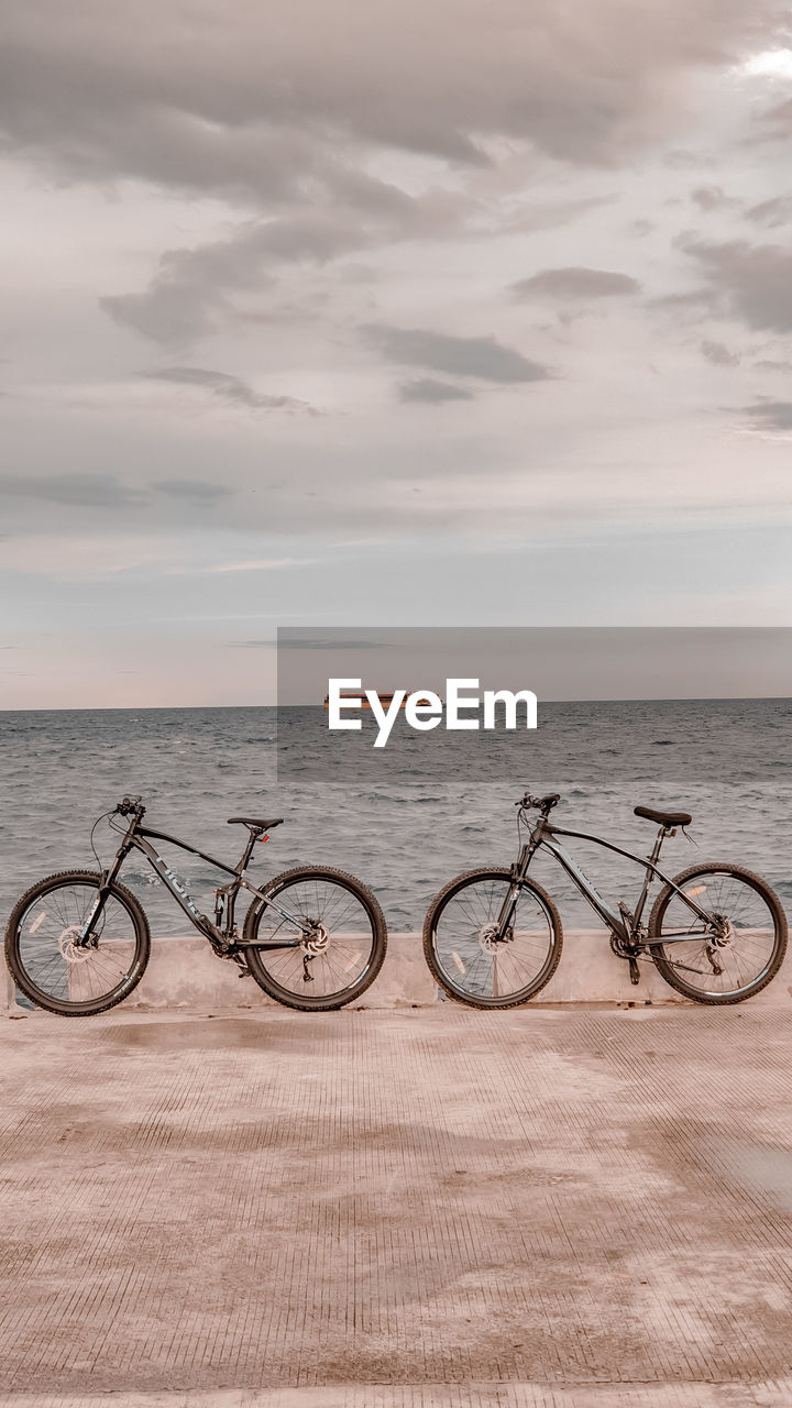 Bicycles by sea against sky