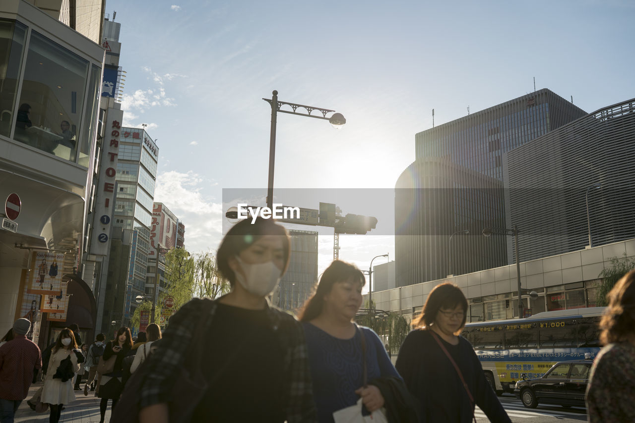 PEOPLE ON STREET BY BUILDINGS AGAINST SKY