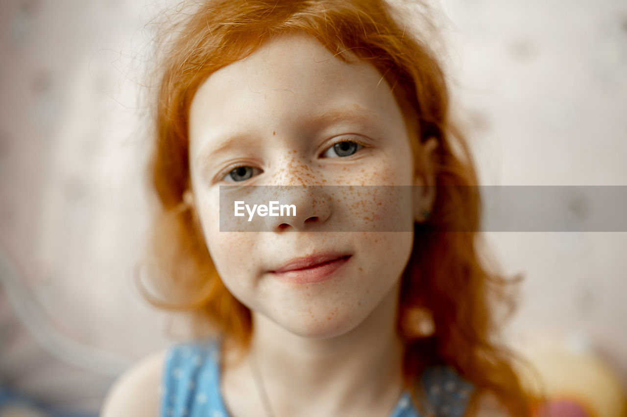 Smiling redhead girl with freckles on face