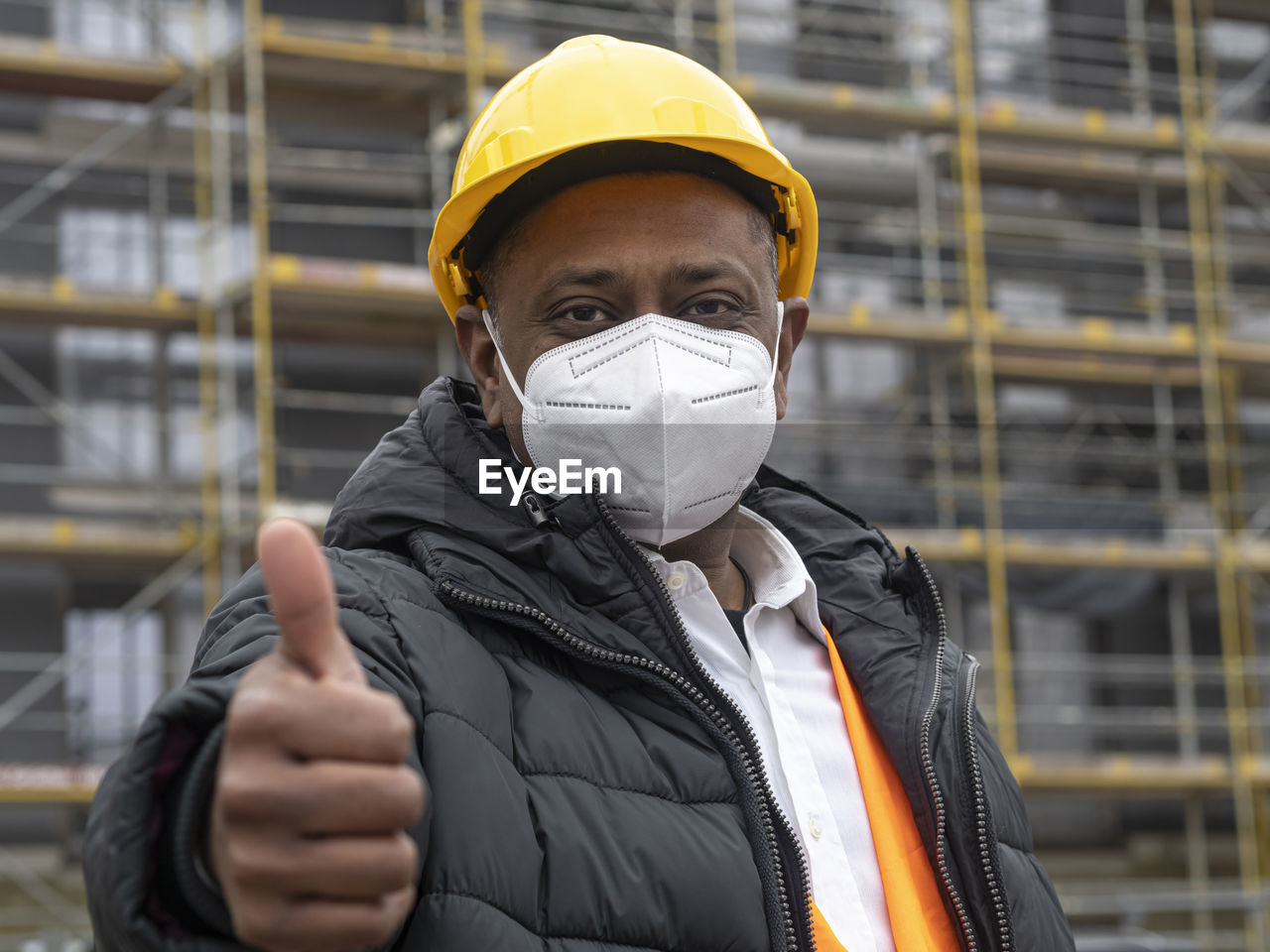 Indian construction worker wearing an ffp2 mask on construction site showing thumbs up gesture