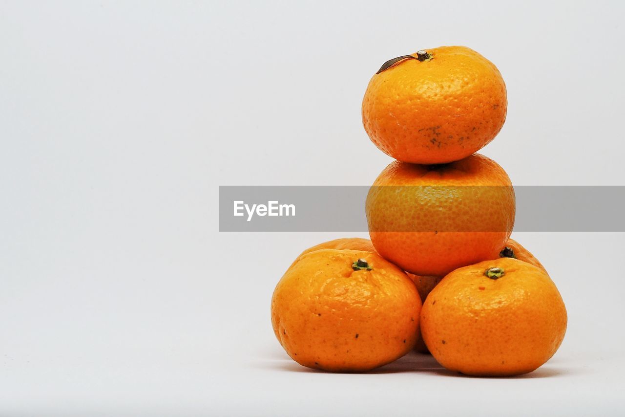 CLOSE-UP OF ORANGES AGAINST WHITE BACKGROUND