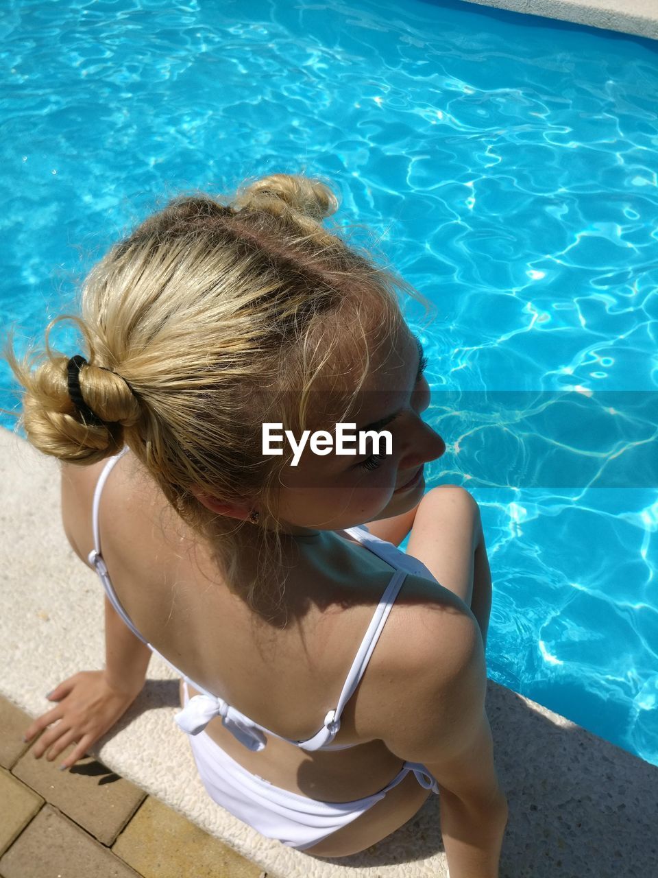 High angle view of teenage girl sitting by swimming pool during summer