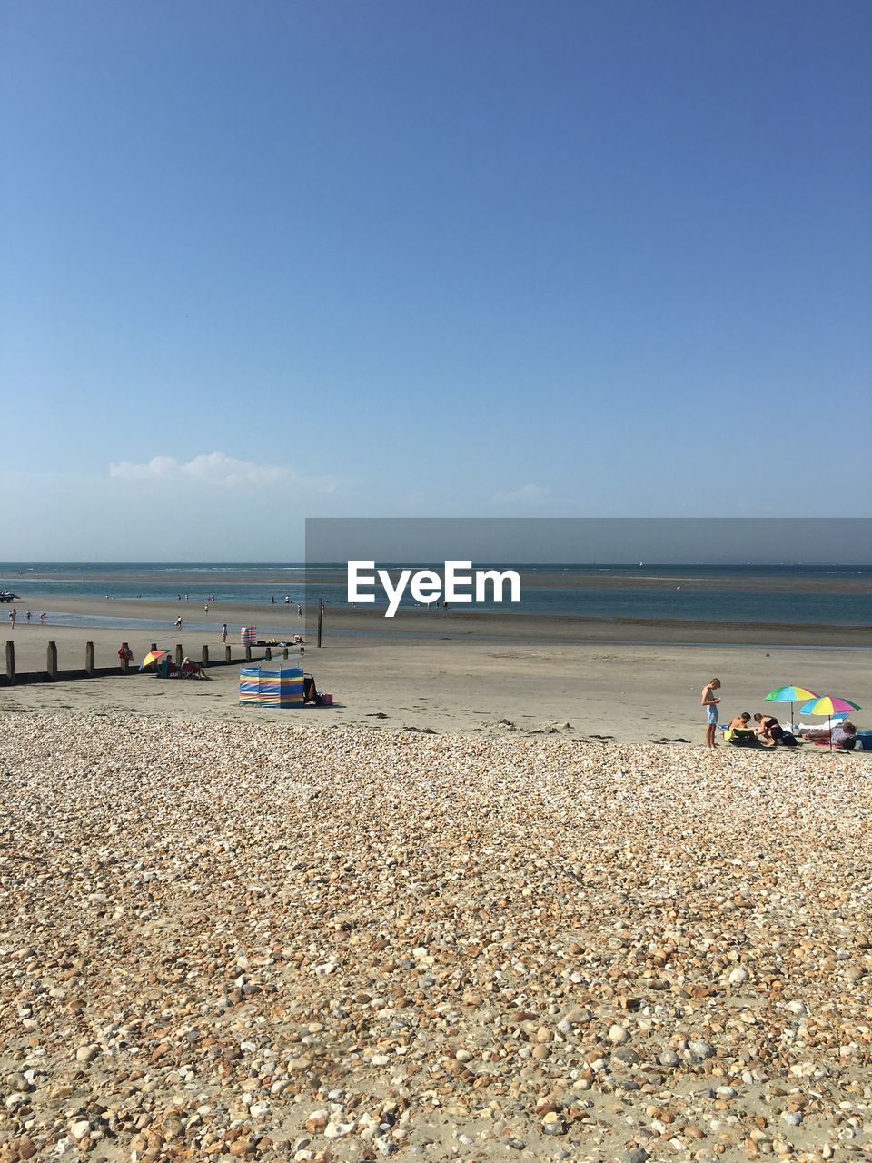 PEOPLE ON BEACH BY SEA AGAINST SKY