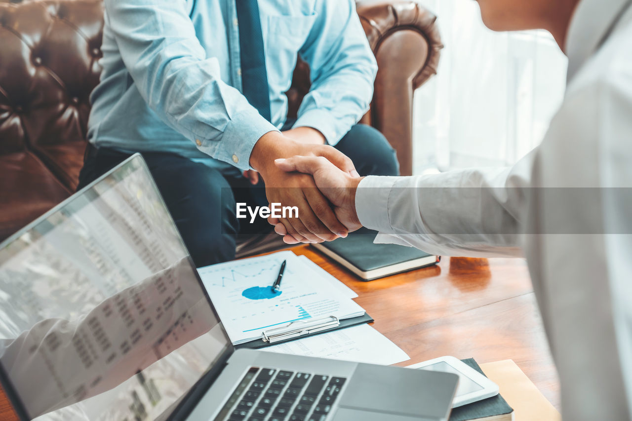 Cropped image of businessmen shaking hands in office