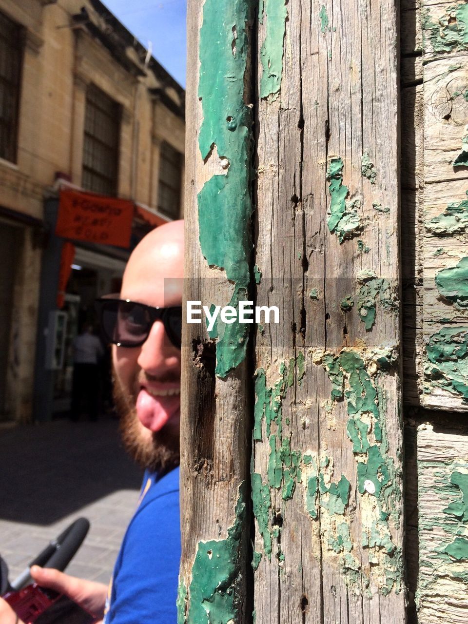 Portrait of man sticking out tongue by wall