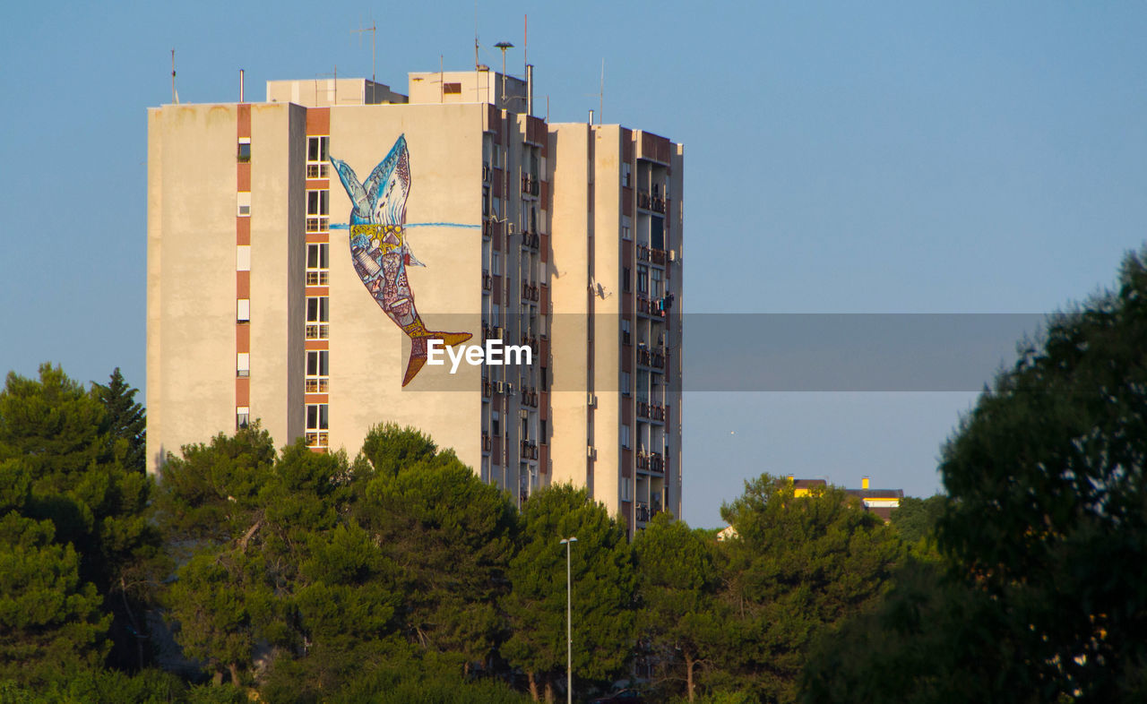 LOW ANGLE VIEW OF FLAG AGAINST BUILDING AGAINST CLEAR SKY