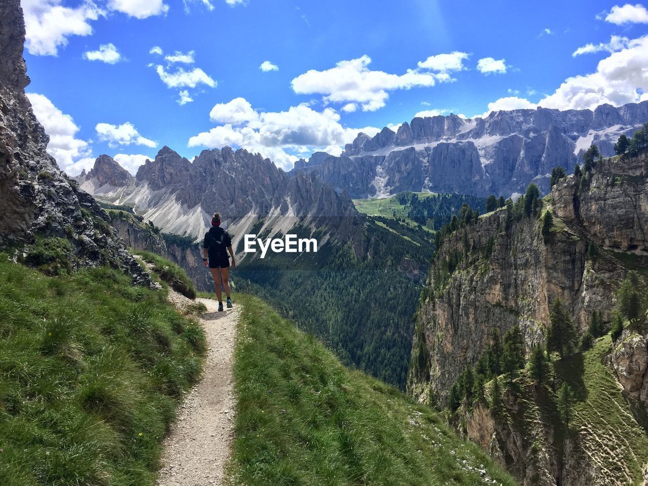 Woman walking on road amidst mountains against sky