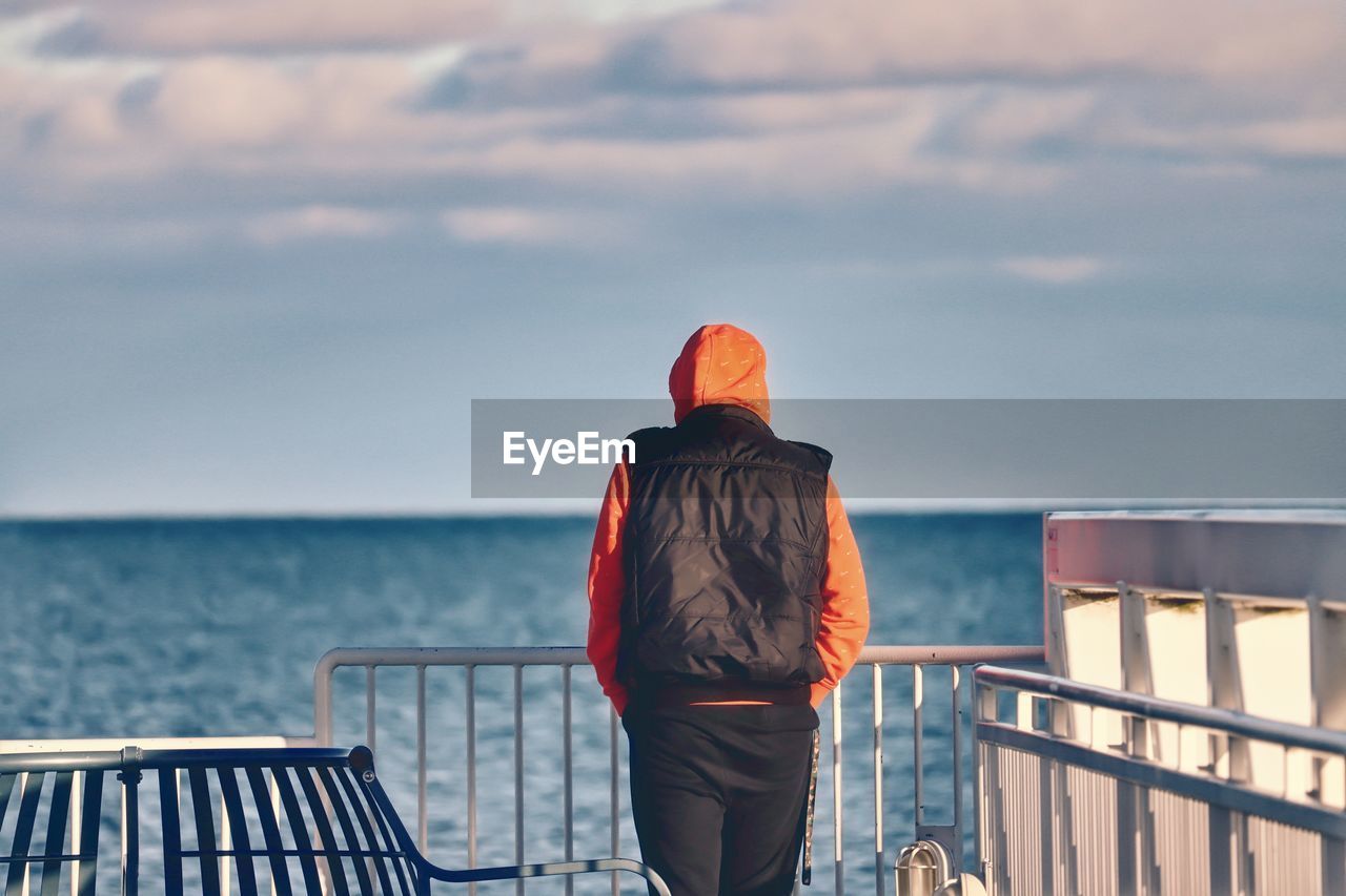 Rear view of man looking at sea against sky