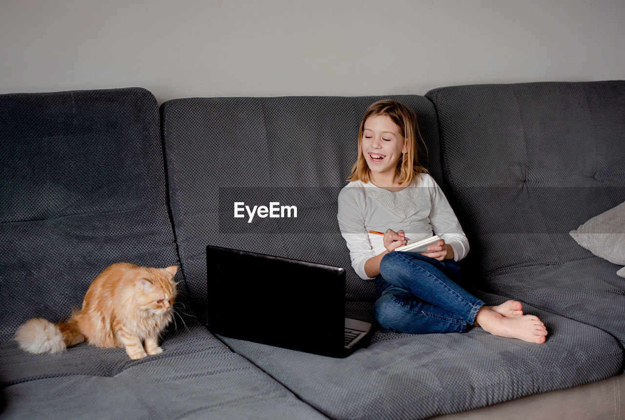 Portrait of young woman using laptop while sitting on sofa at home