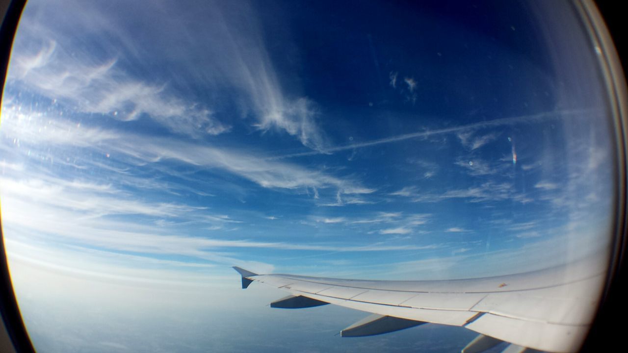 View of aircraft wing against blue sky seen from window