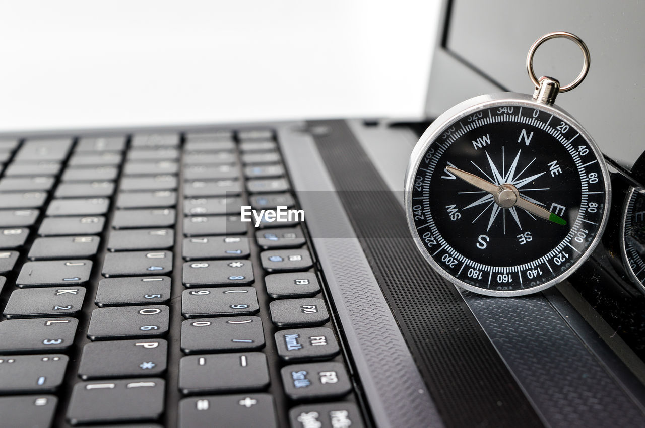 Close-up of navigational compass on laptop against white background