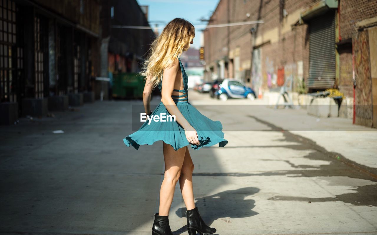 FULL LENGTH OF WOMAN WALKING ON COBBLESTONE