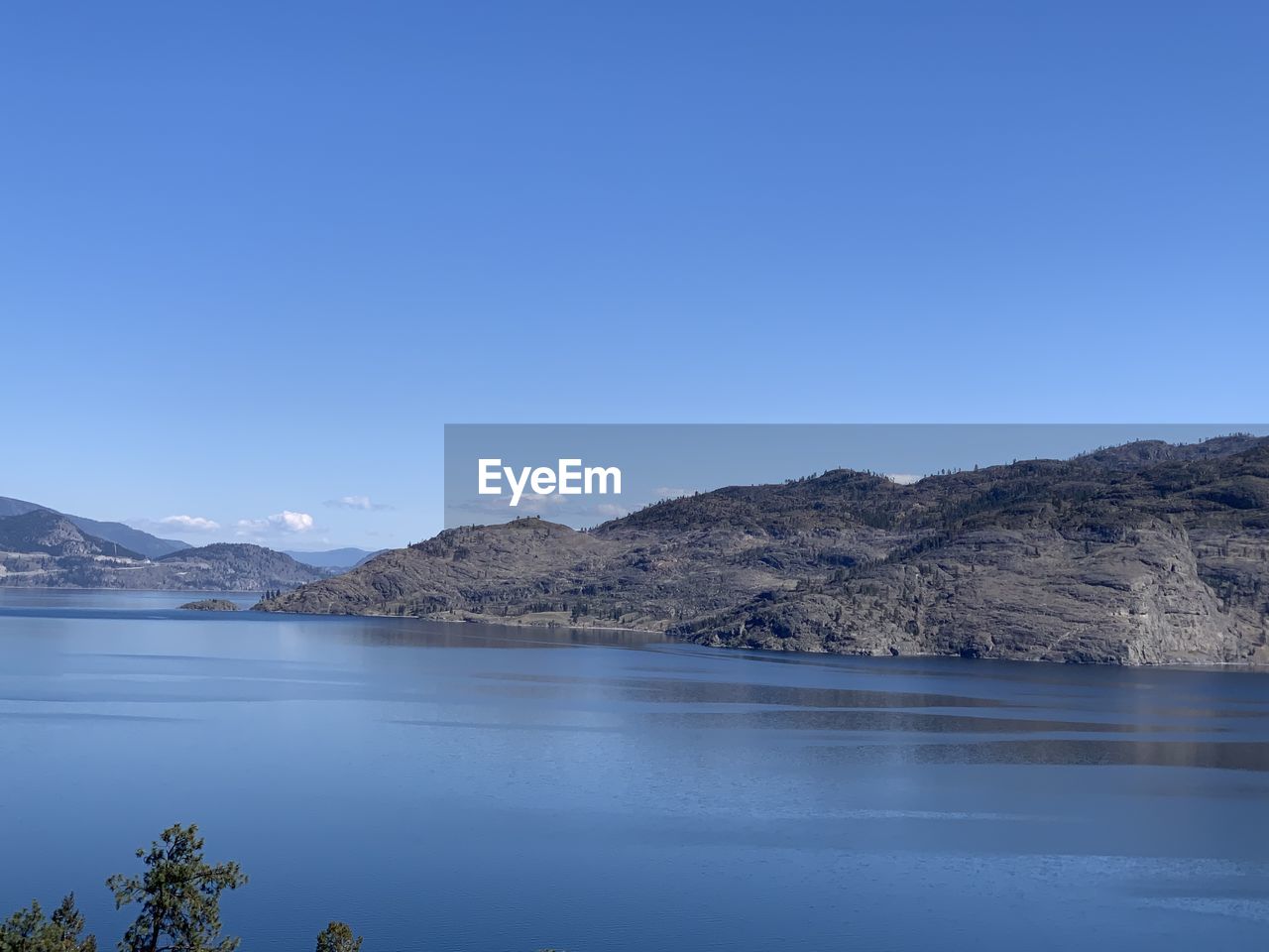 Scenic view of lake and mountains against clear blue sky