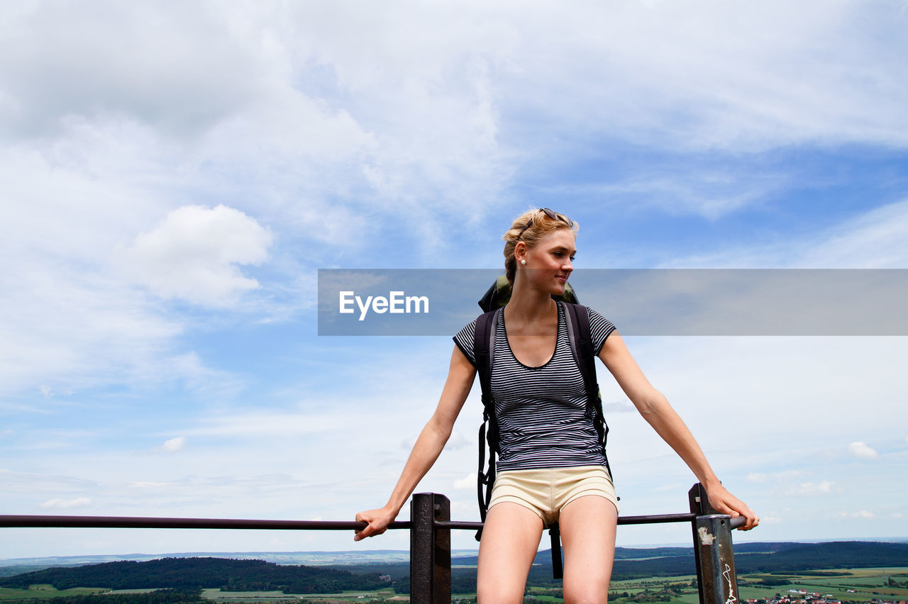 Young woman sitting on railing at observation point