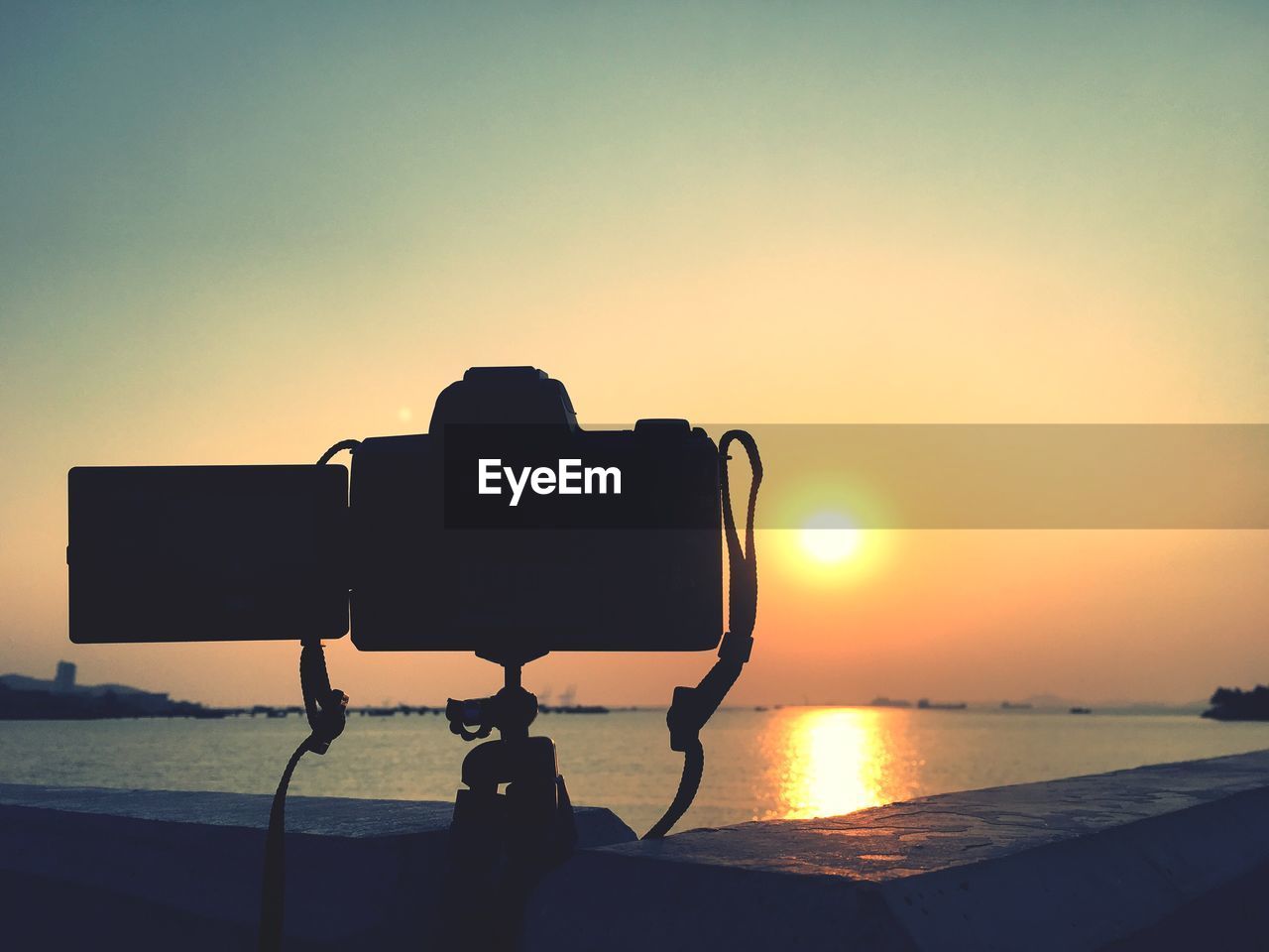 SILHOUETTE PHOTOGRAPHING BY SEA AGAINST ORANGE SKY