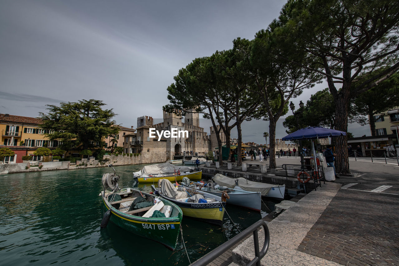 BOATS MOORED IN CANAL BY BUILDINGS AGAINST SKY