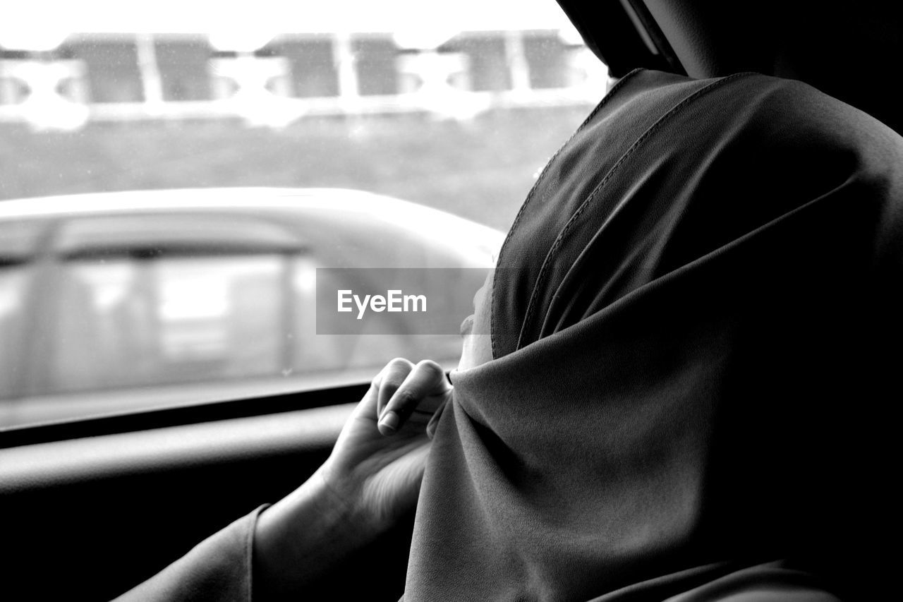 Close up of woman looking through window in car