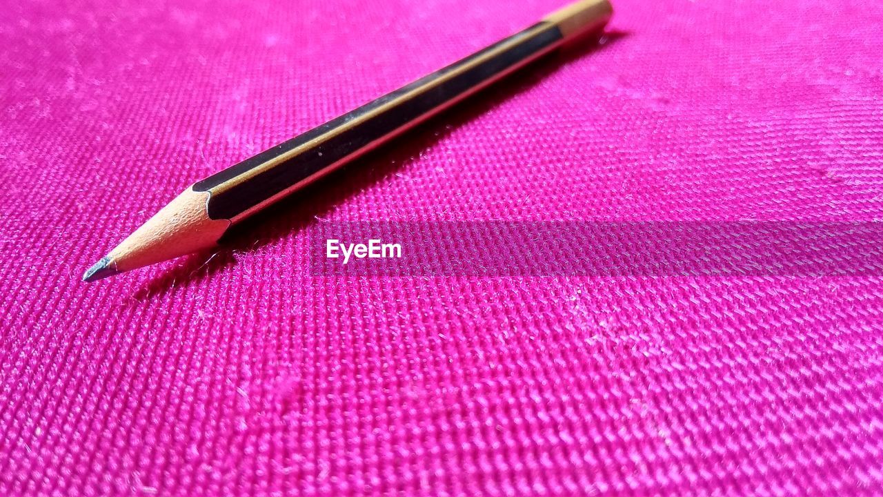 HIGH ANGLE VIEW OF COLORED PENCILS ON PINK PEN