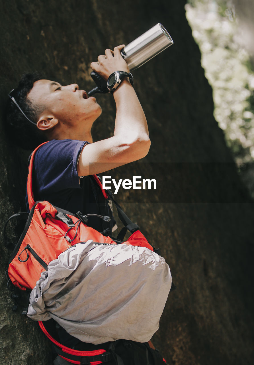 Side view of man holding camera while standing on land