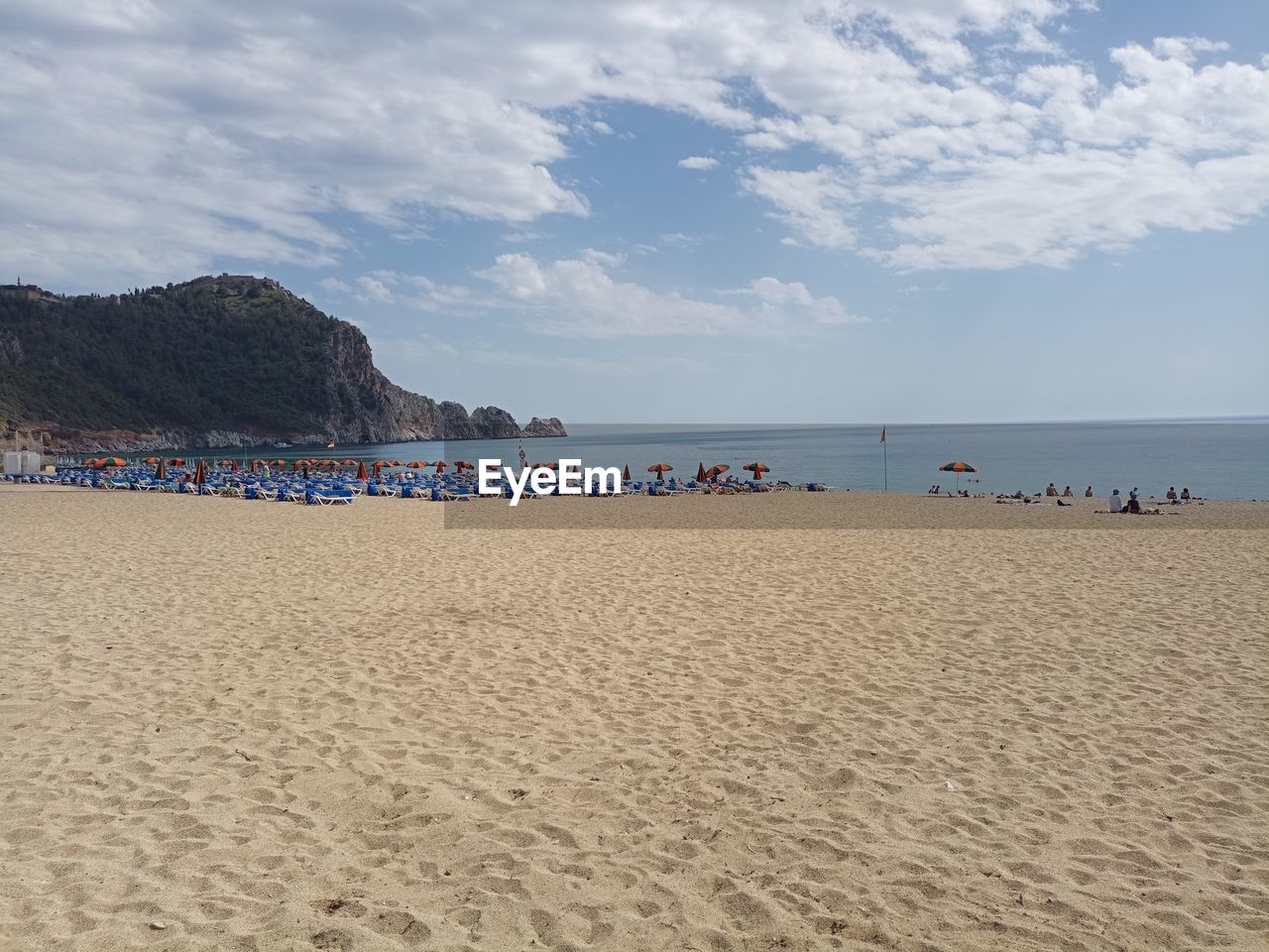 land, beach, sea, water, sand, sky, body of water, holiday, vacation, trip, nature, cloud, scenics - nature, travel destinations, shore, beauty in nature, travel, coast, tourism, summer, coastline, ocean, group of people, large group of people, tranquility, crowd, hut, horizon over water, tourist, outdoors, environment, day, tranquil scene, water's edge, relaxation, blue, leisure activity, seascape, horizon, architecture, chair, singing sand, sun, landscape, idyllic, sports, non-urban scene