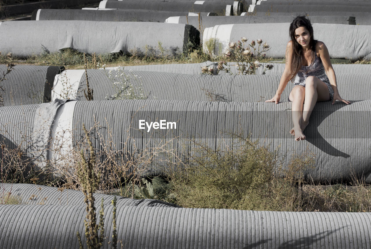 Full length of woman sitting on rolled grass outdoor, staduim