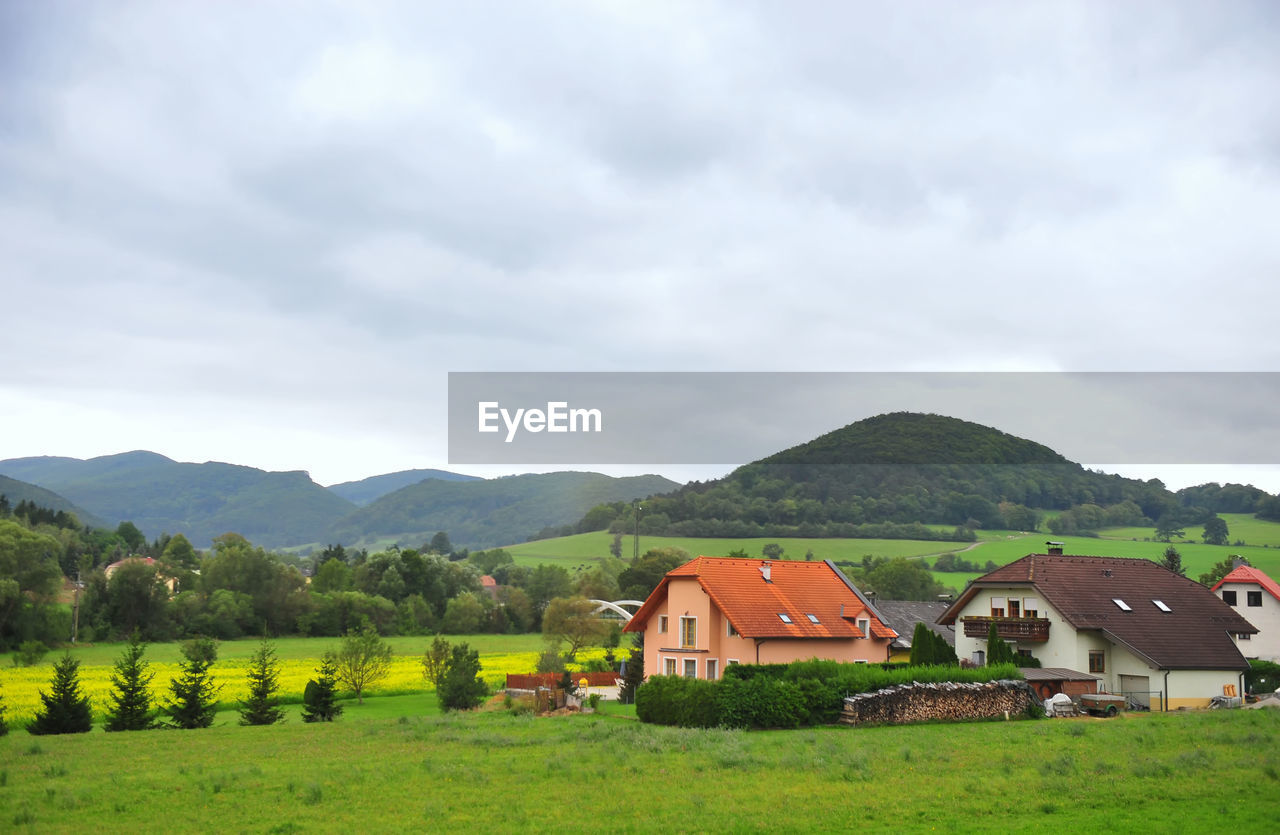 Houses on landscape against cloudy sky