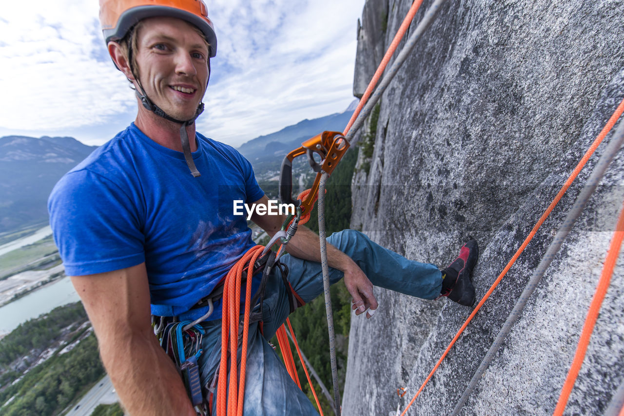 Man resting while rock climbing hanging on rope with ascender