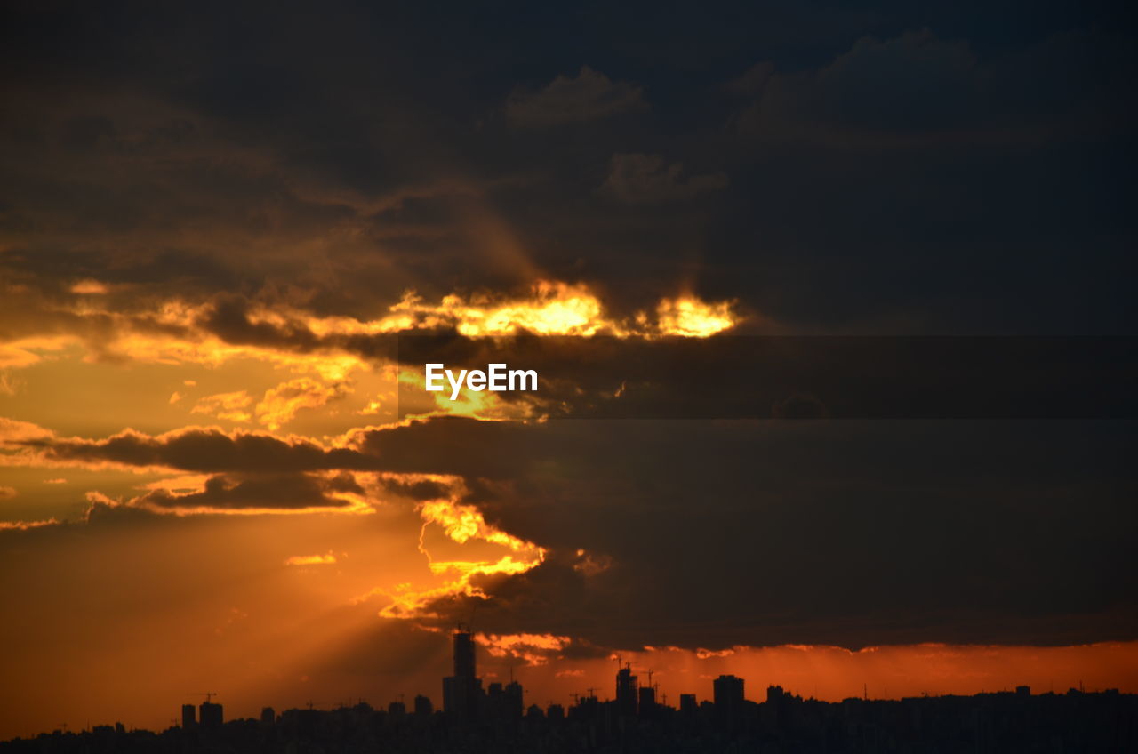 Silhouette buildings against orange sky during sunset