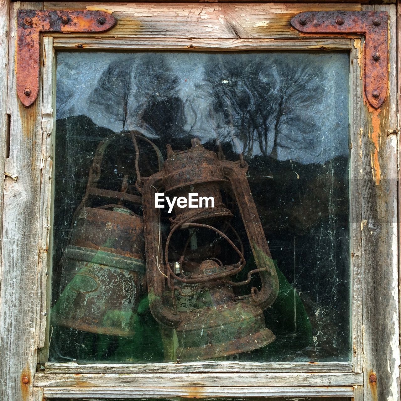 Close-up of old rusty oil lamps inside glass window