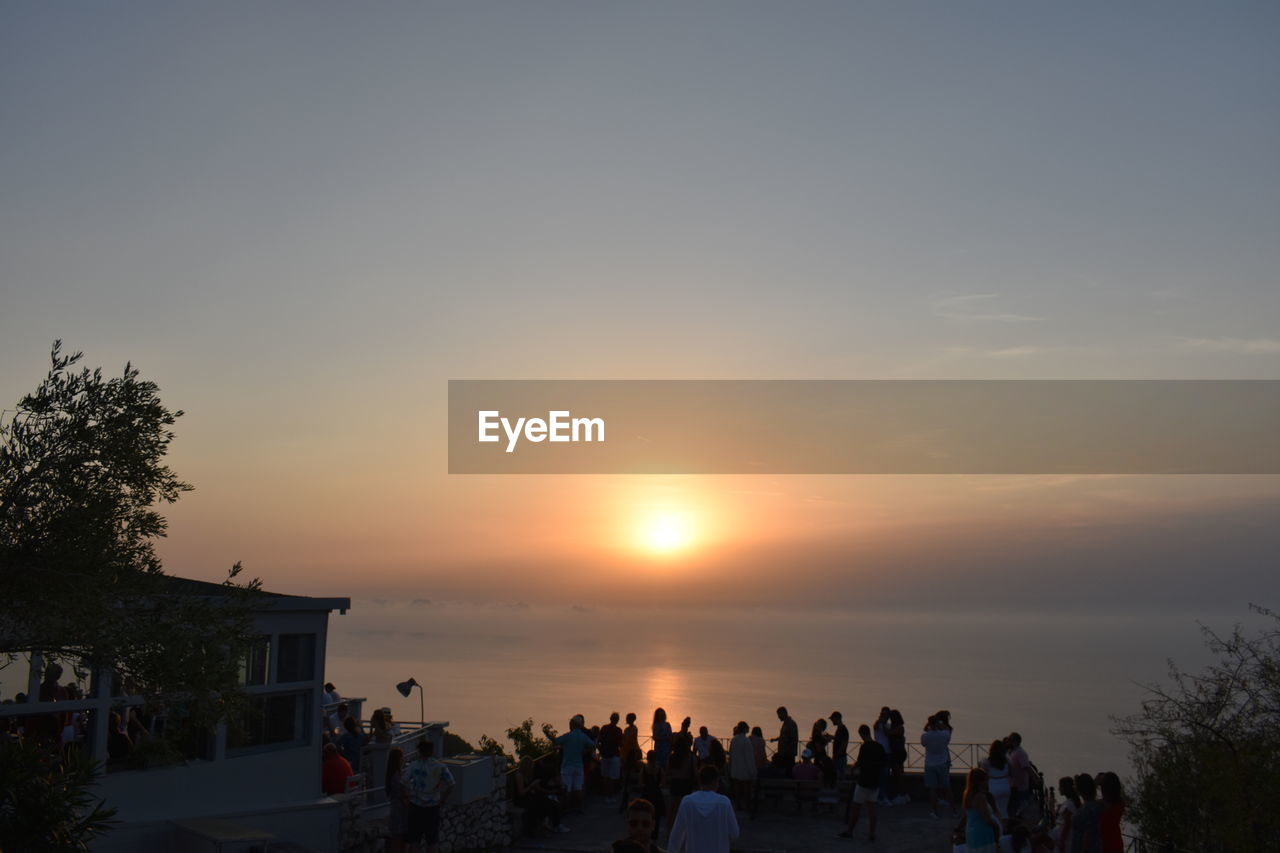 sky, sunset, group of people, large group of people, crowd, evening, nature, dusk, water, sea, lifestyles, leisure activity, tree, horizon, silhouette, sun, men, beauty in nature, architecture, women, plant, beach, adult, land, scenics - nature, outdoors, holiday, vacation, trip, enjoyment, sunlight, travel, copy space, cloud, travel destinations, orange color