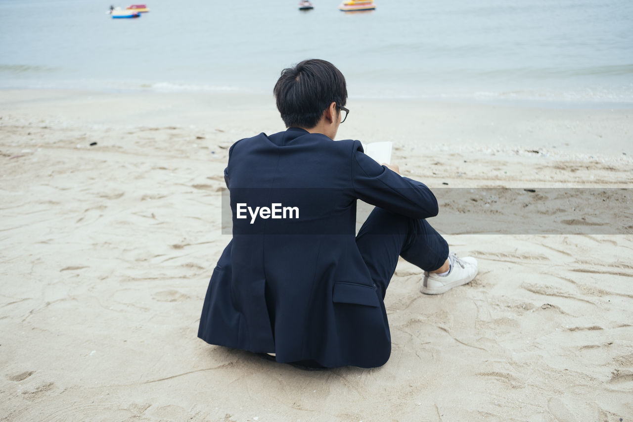 REAR VIEW OF A BOY ON BEACH