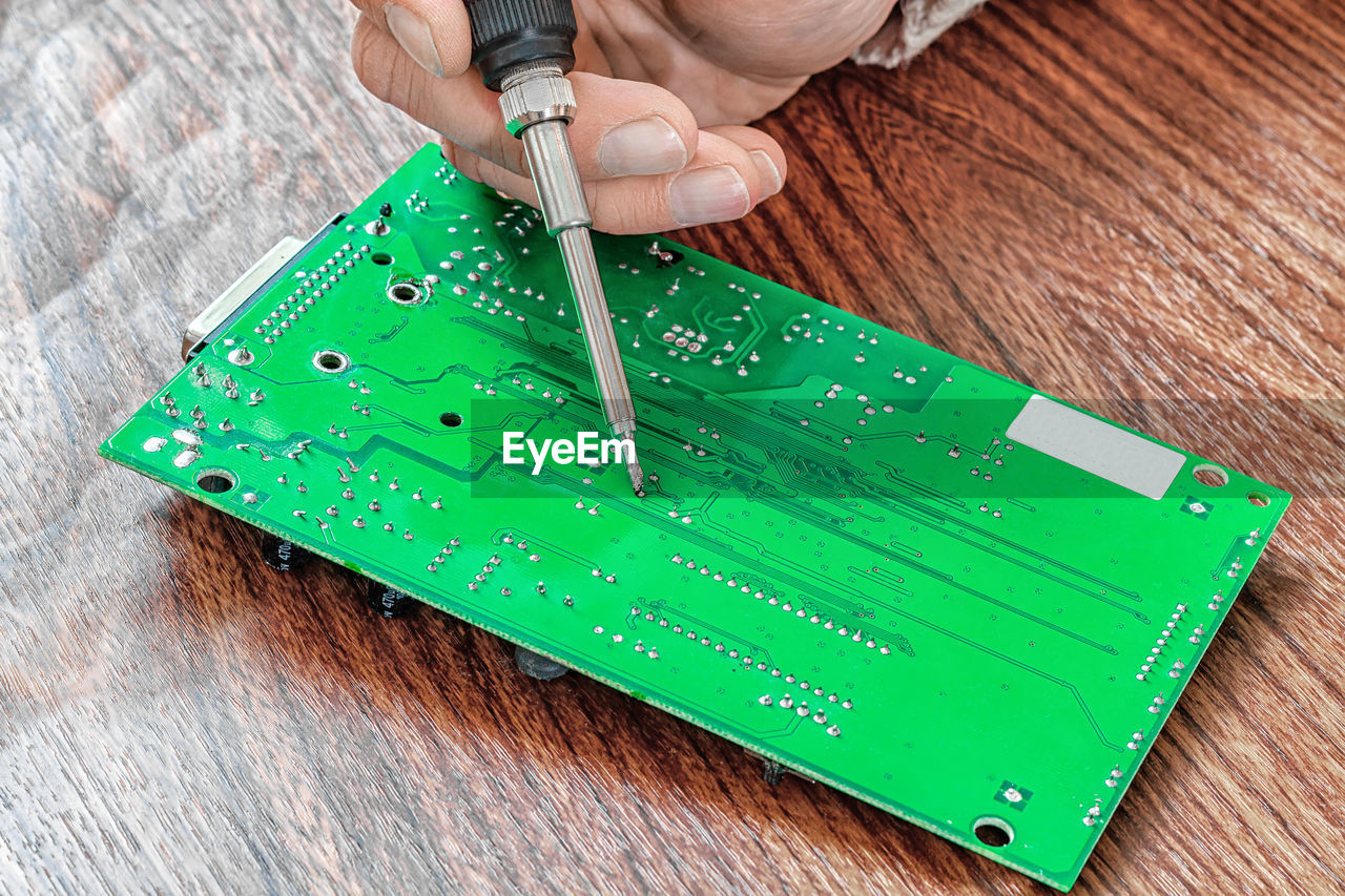 green, one person, hand, wood, indoors, equipment, adult, working, close-up, circuit board, industry, technology, holding, occupation