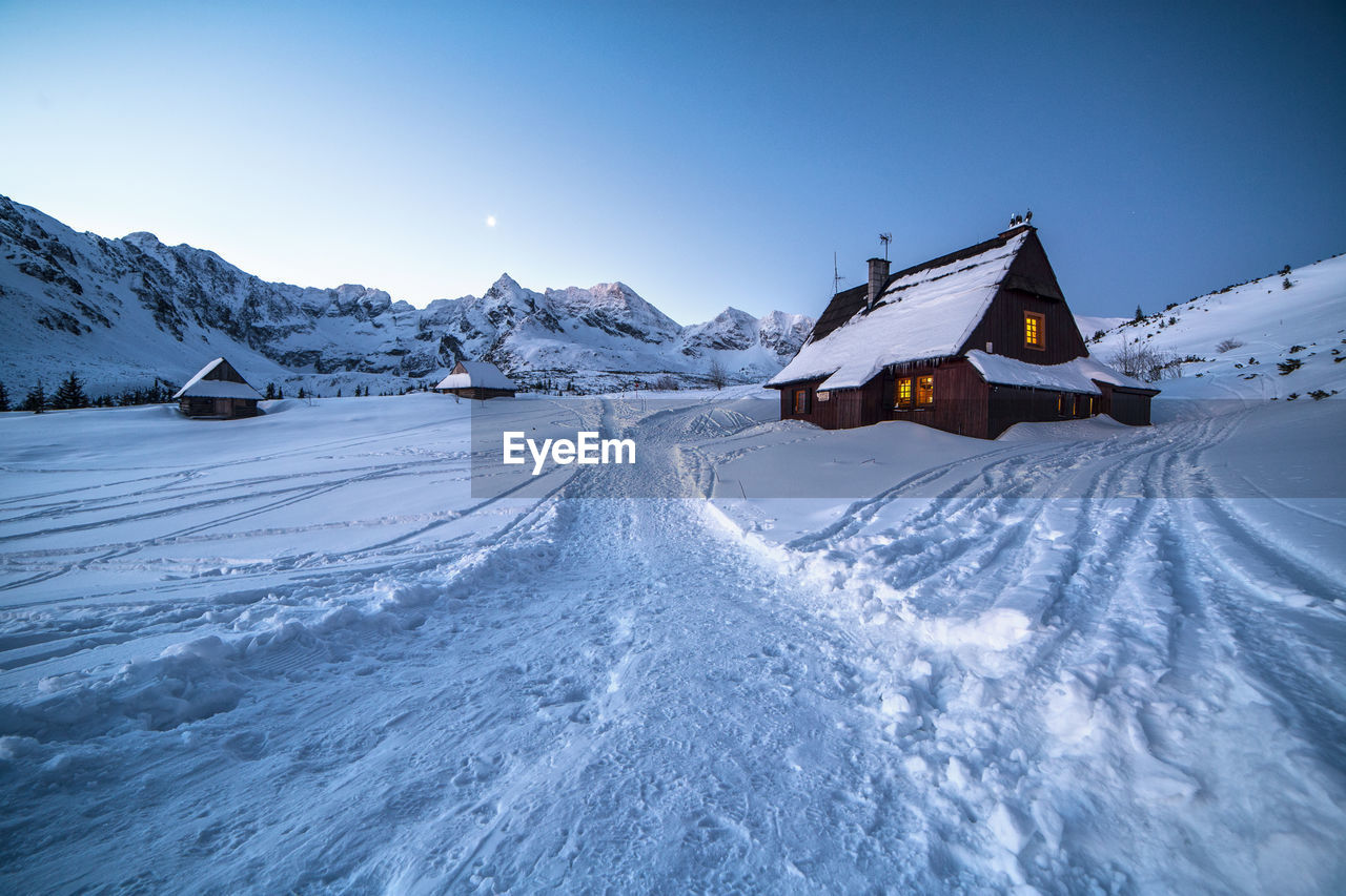 SNOW COVERED LAND AGAINST MOUNTAIN