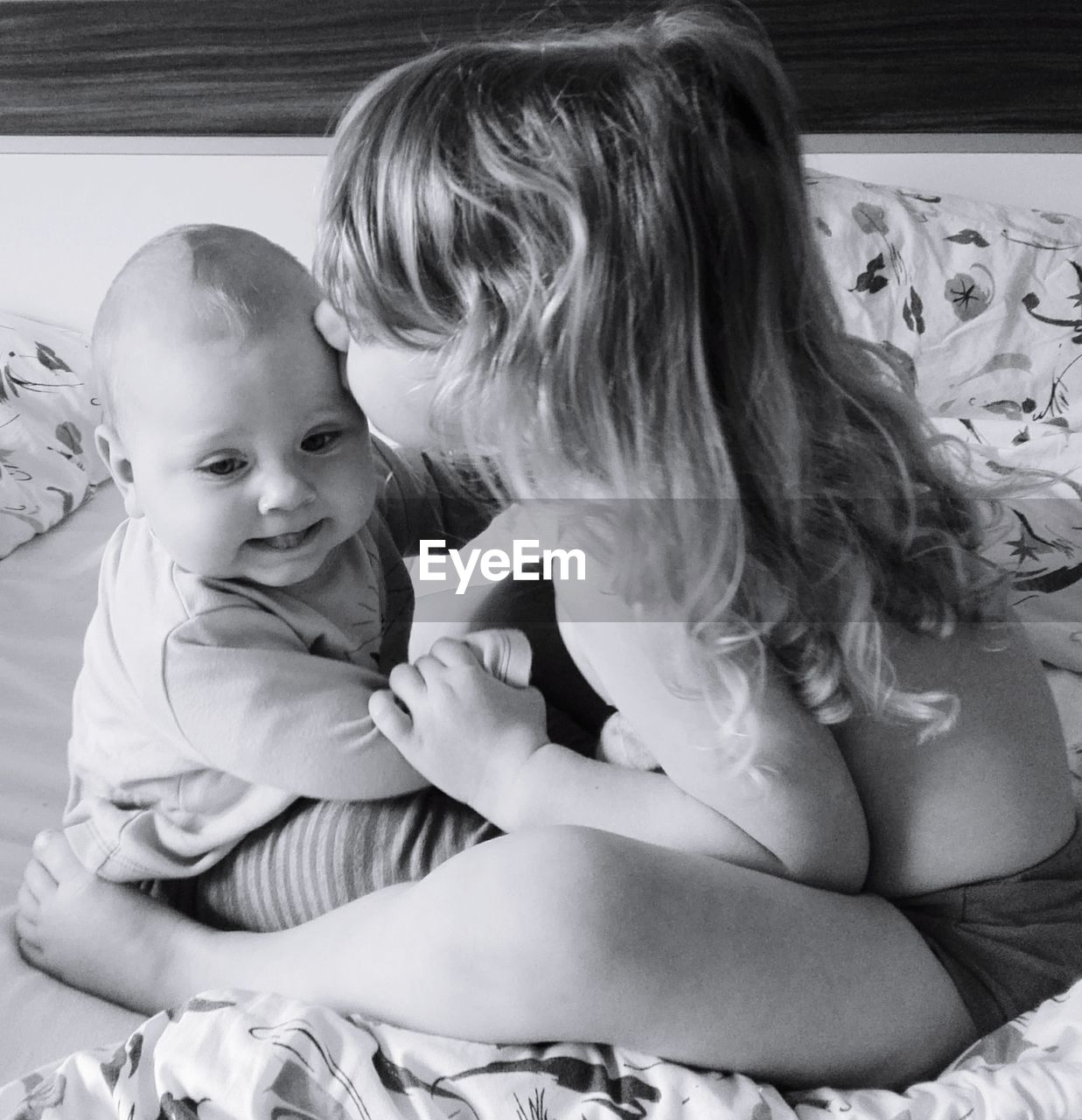 high angle view of mother and daughter sitting on bed at home