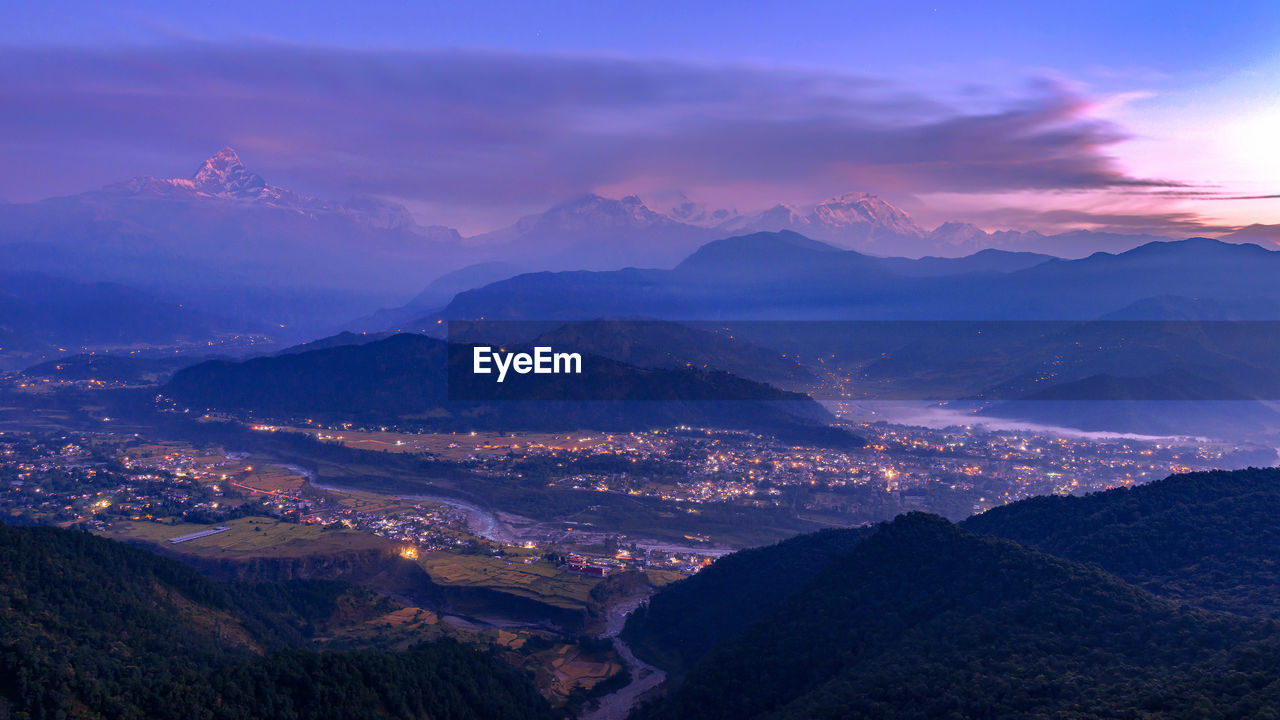 AERIAL VIEW OF MOUNTAINS AGAINST SKY AT SUNSET
