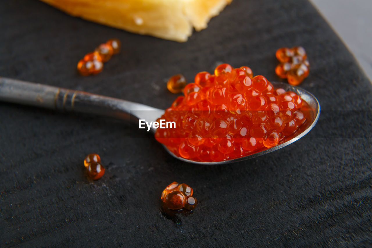 Spoon with red caviar on a black wooden background. horizontal photo