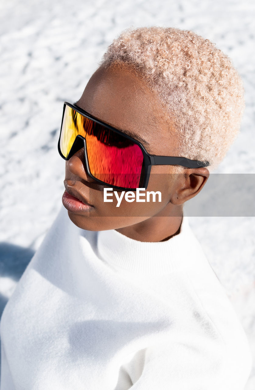 A young african american woman wearing sunglasses having fun in the snow on a winter day