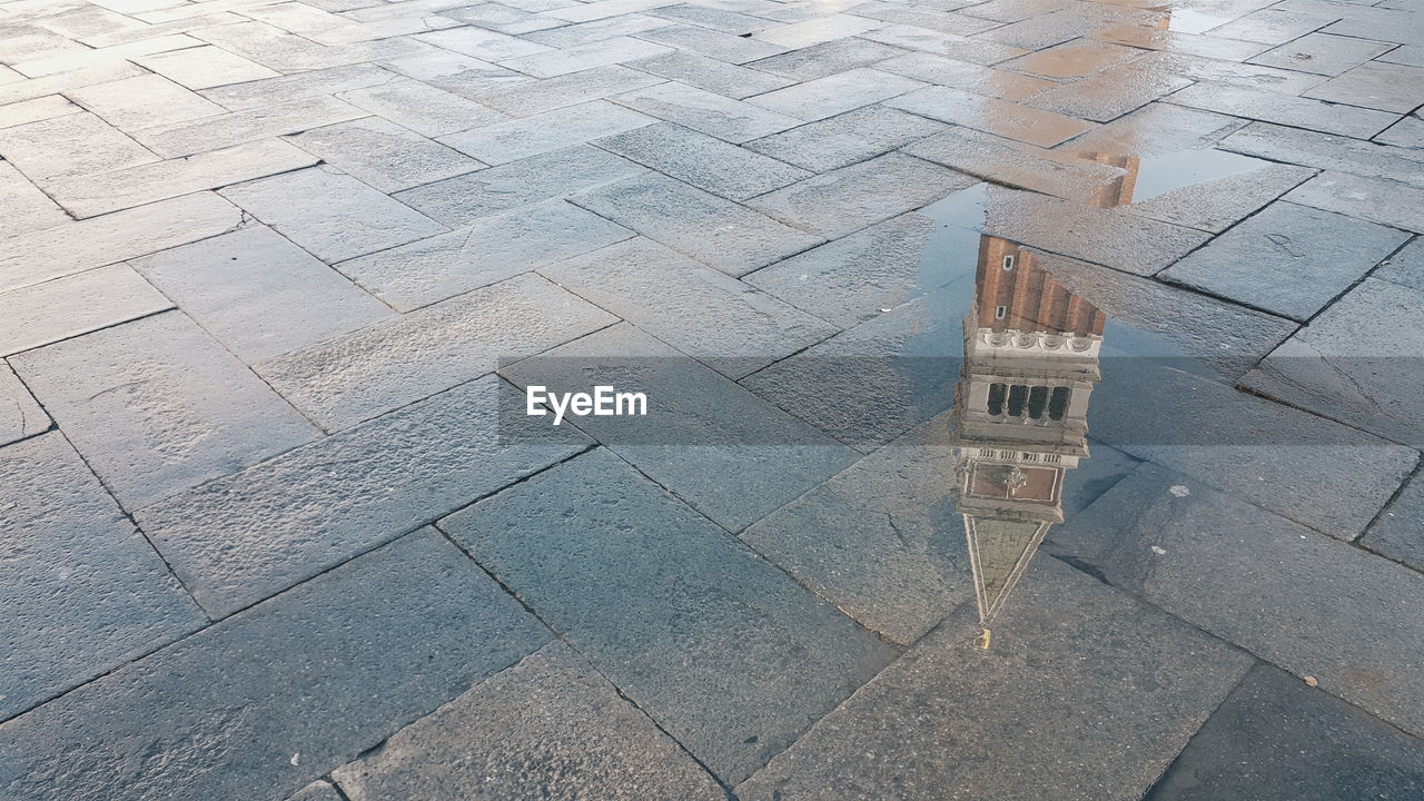 Reflection of san marco campanile on puddle at street