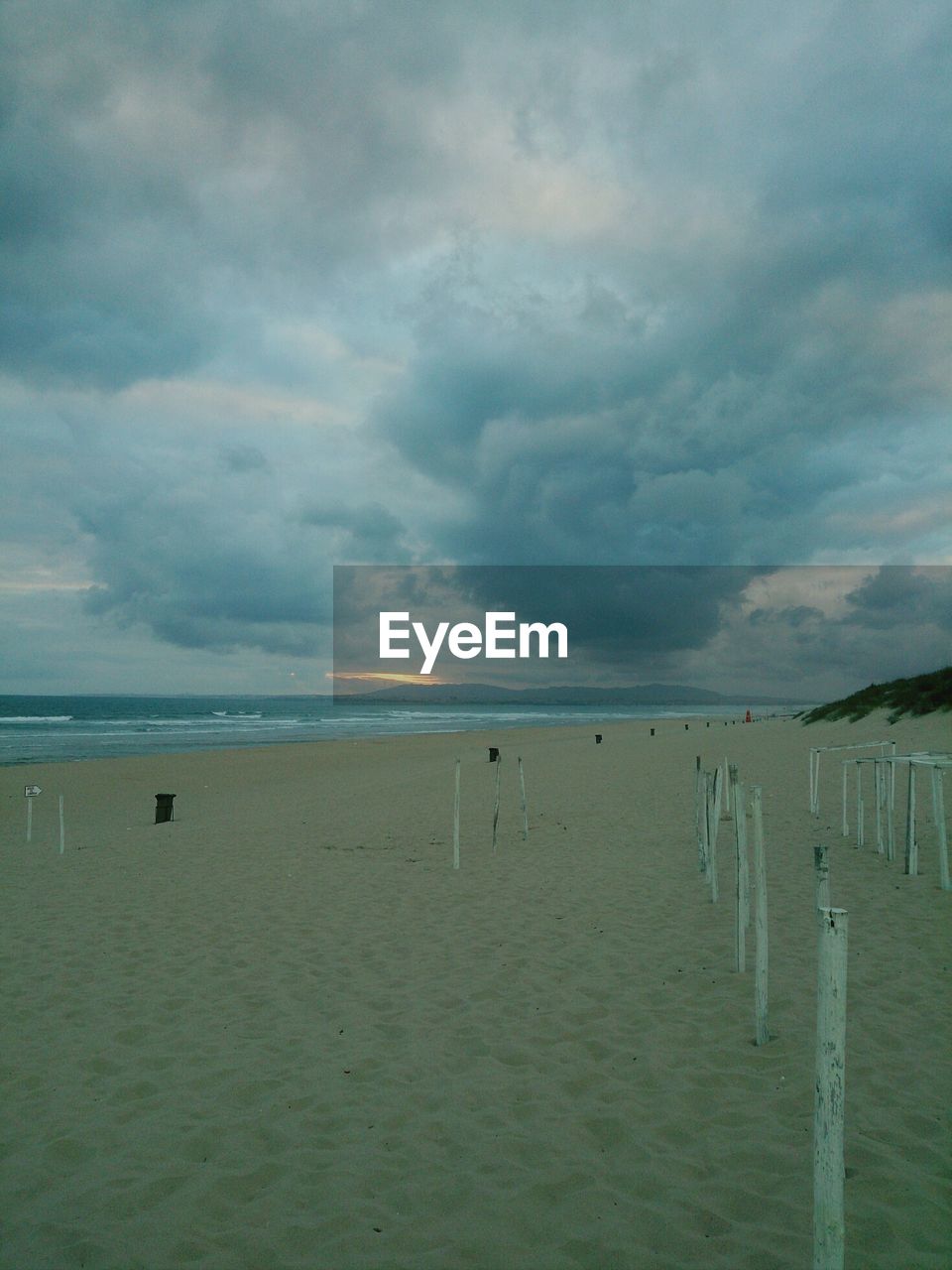 Scenic view of beach against cloudy sky